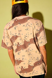 Back view of a model wearing a camo shirt on a pale yellow background