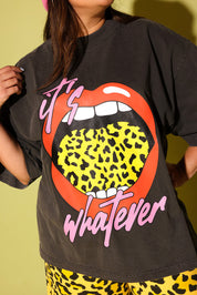 Close up of a model wearing a gray tee with lips and yellow leopard tongue and pink text that reads 'it's whatever' on a pale  yellow background