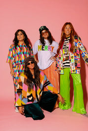 A group of models wearing colorful Christmas themed outfits on a pink background