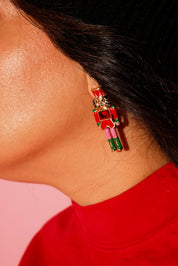 Close up of a model wearing a red crewneck with earrings in the shape of a nutcracker
