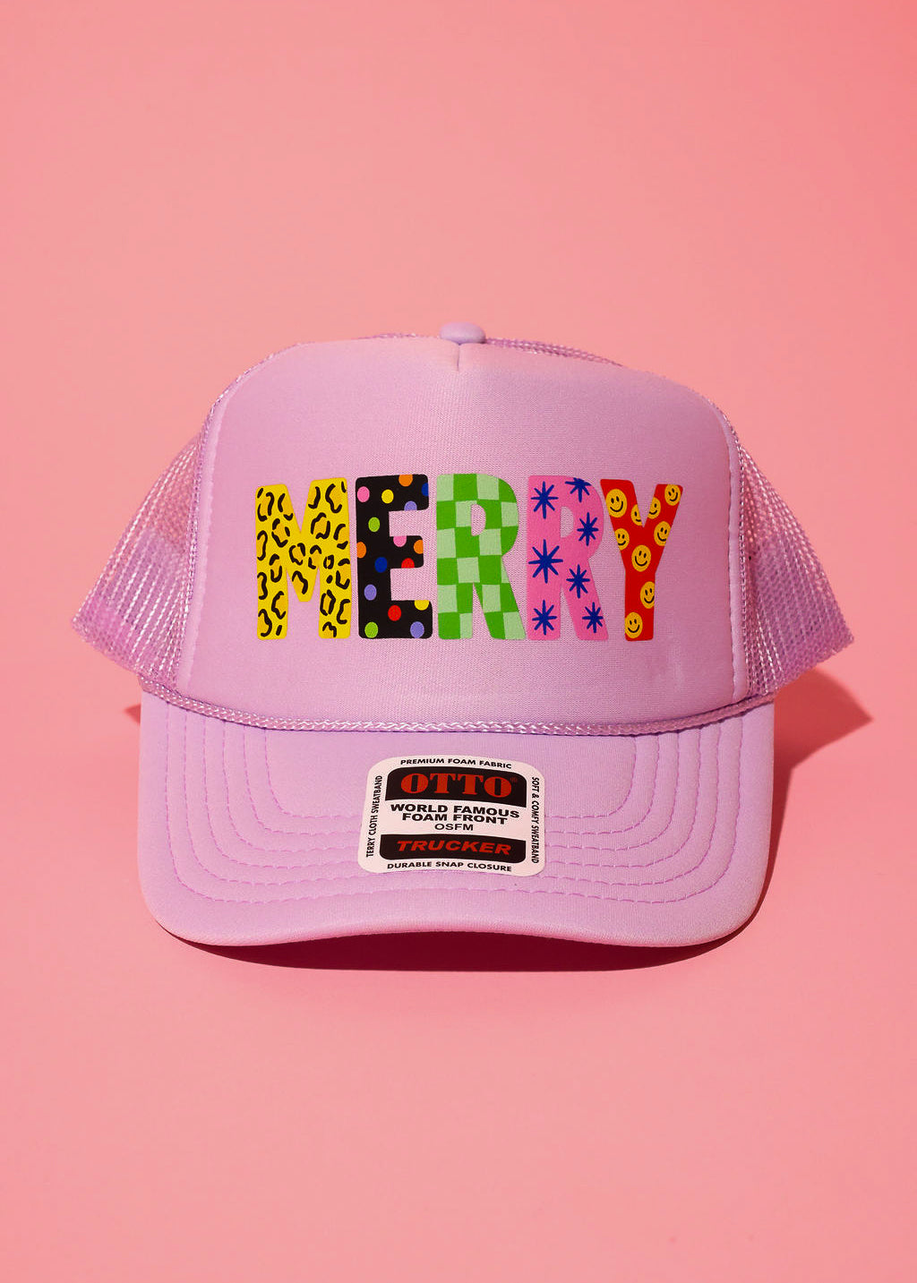 Lavender trucker hat with the text 'MERRY' in different patterns on a pink background