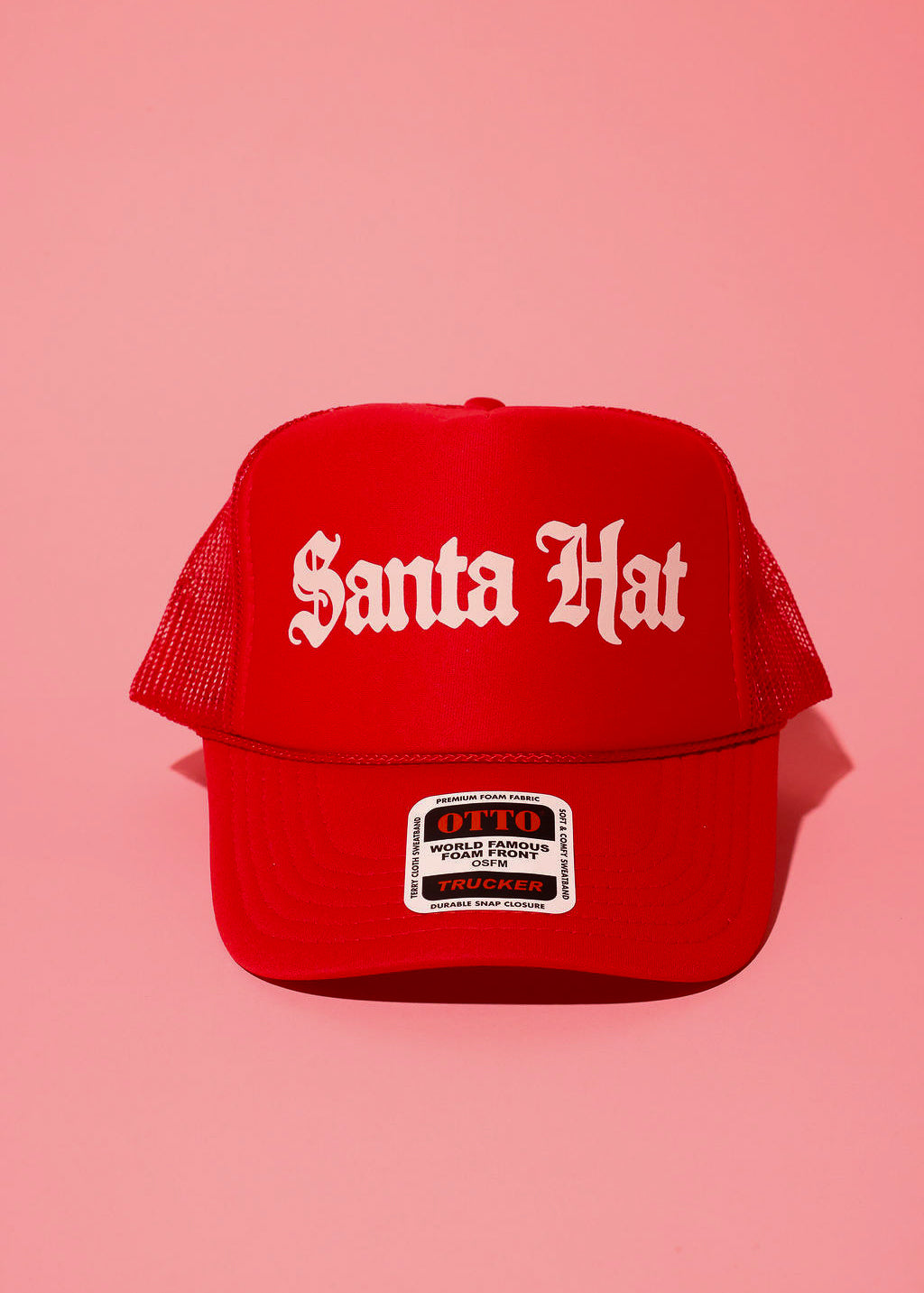 Red trucker hat with white text that reads 'Santa Hat' on a pink background