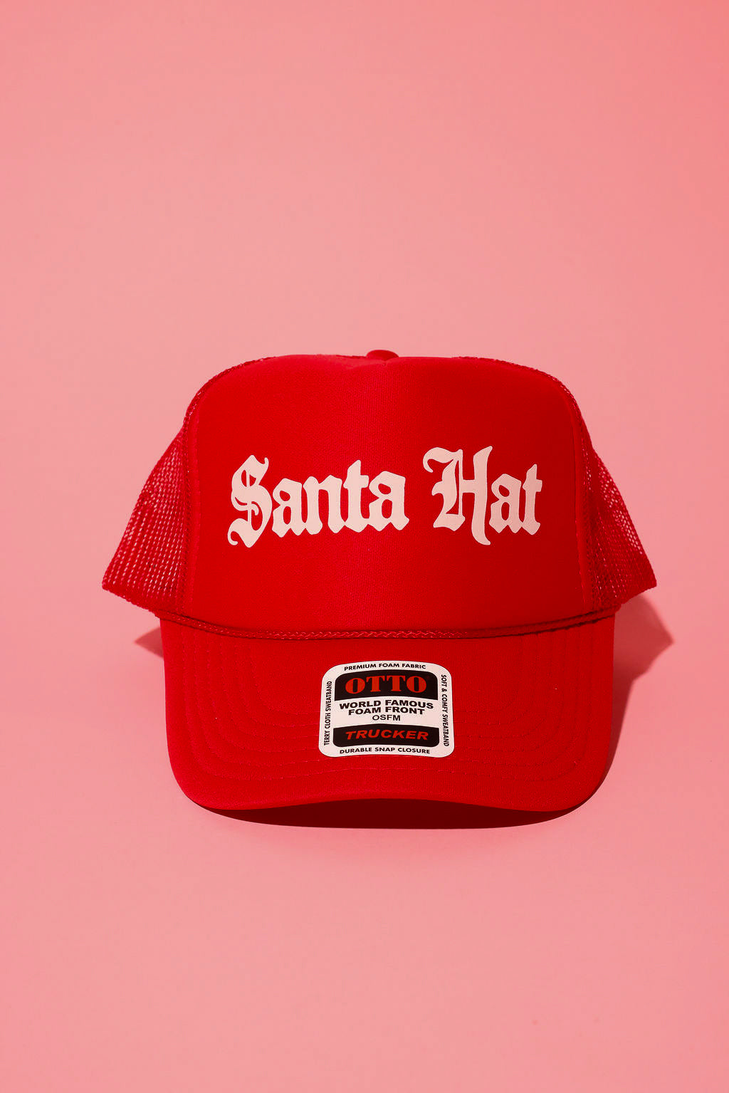 Red trucker hat with white text that reads 'Santa Hat' on a pink background