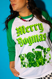 A model wearing jeweled wreath earrings and necklace and a green Christmas baseball tee on a blue background