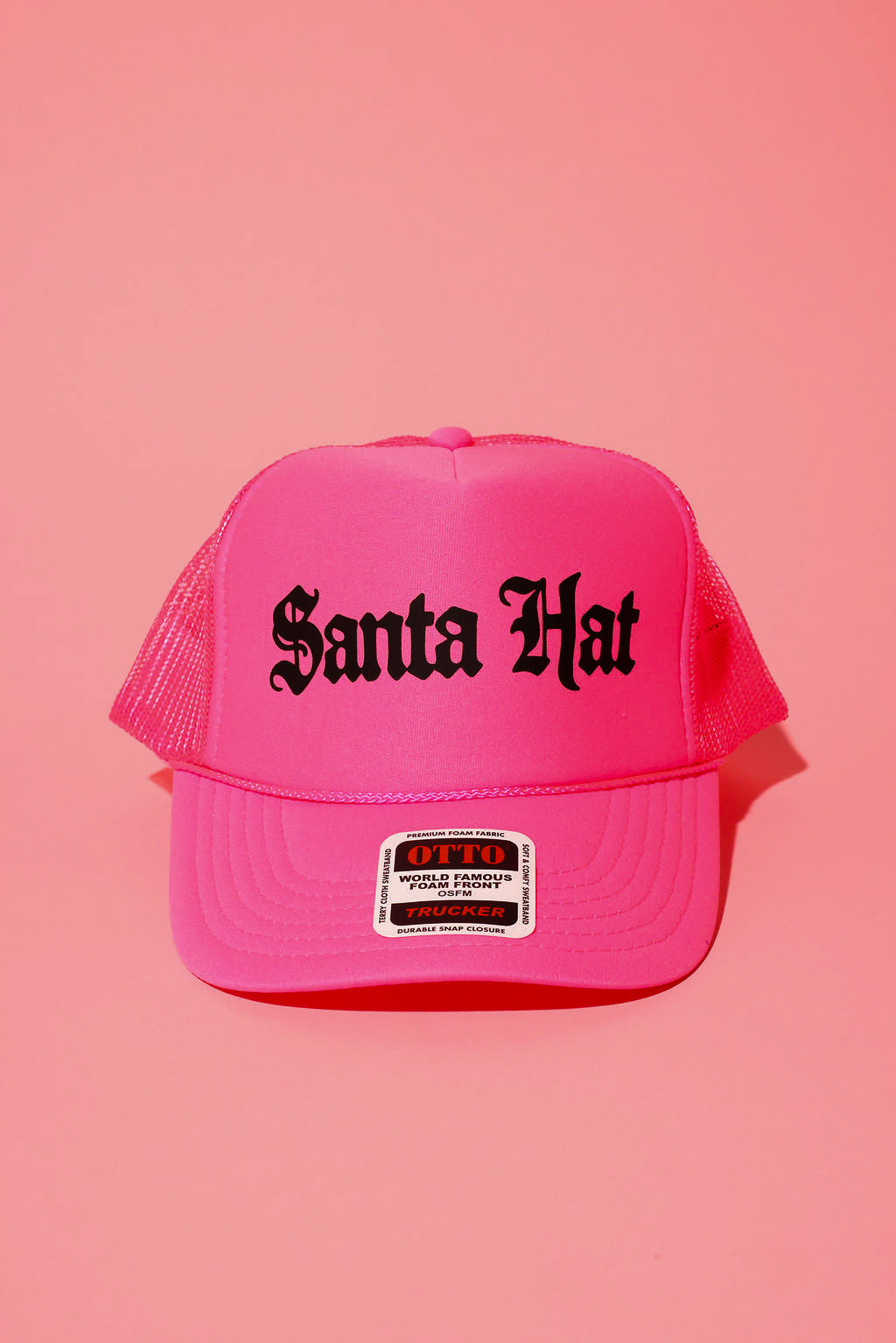 Neon pink trucker hat with black text that reads 'Santa Hat' on a pink background