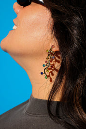 Model wearing a grey tee sunglasses and dangly earrings with multi-colored jewels
