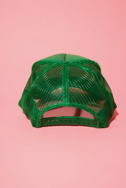 Back view of a green mesh trucker hat on a pink background