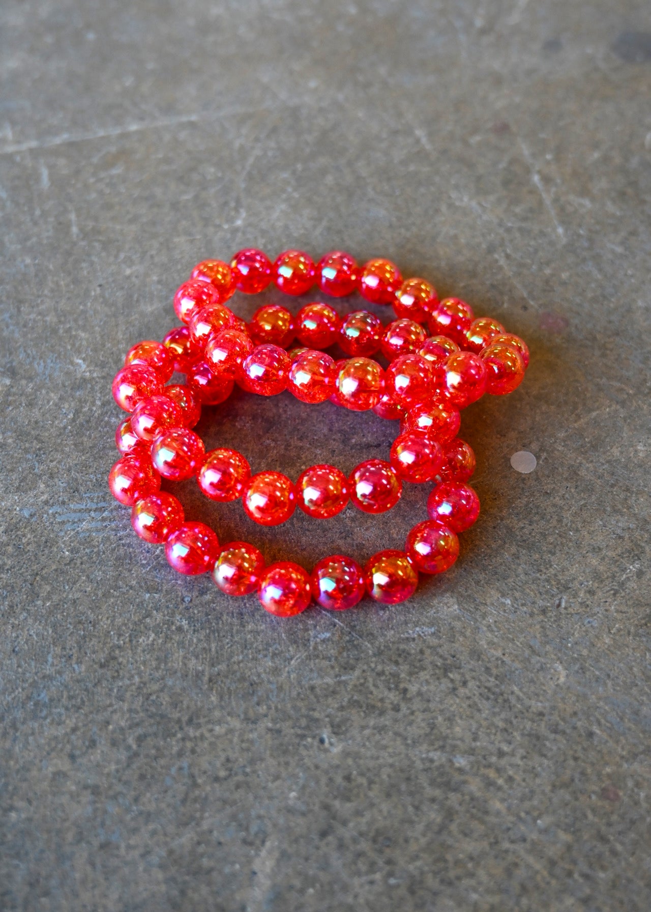 A stack of three pink beaded bracelets on a dark background