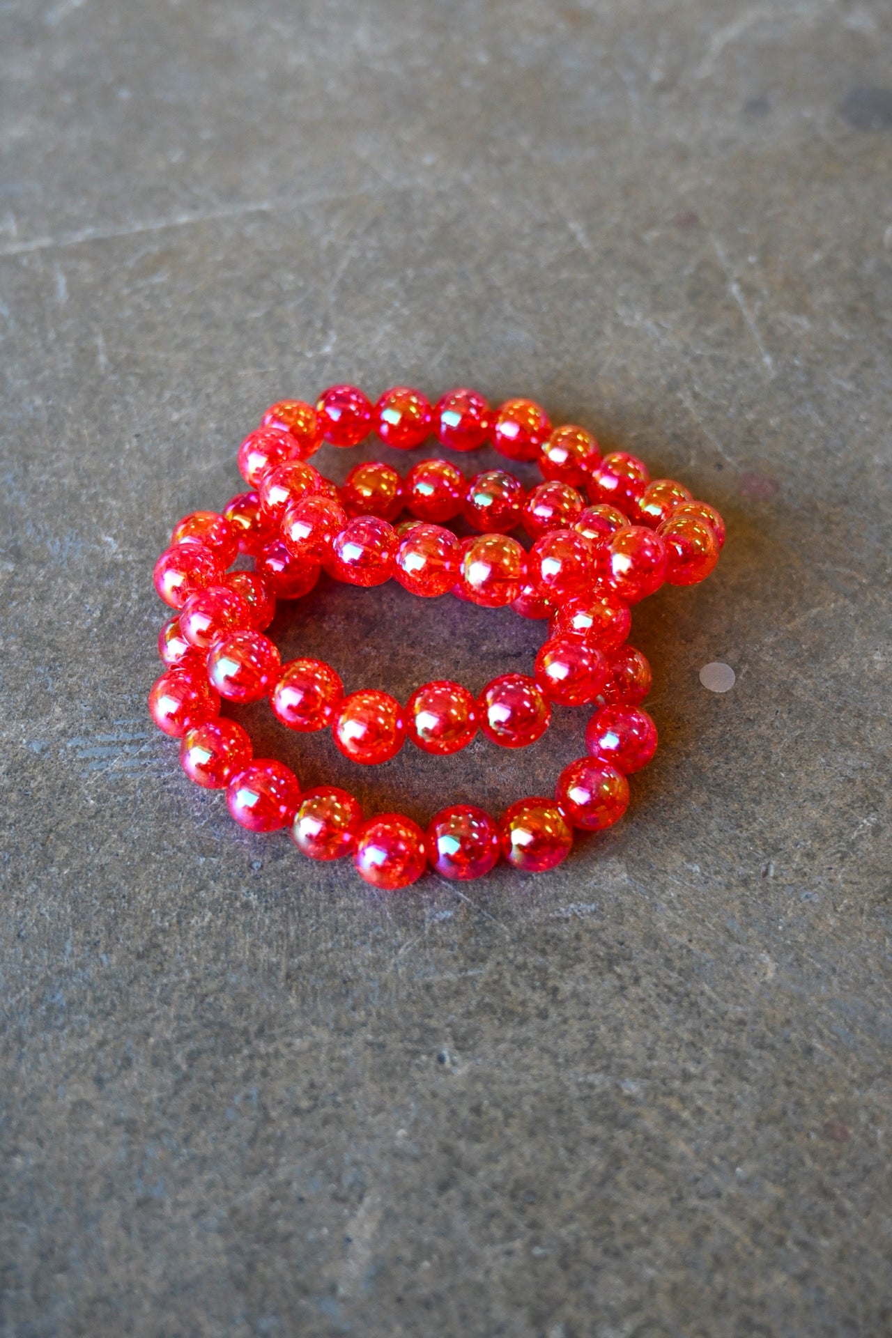 A stack of three pink beaded bracelets on a dark background