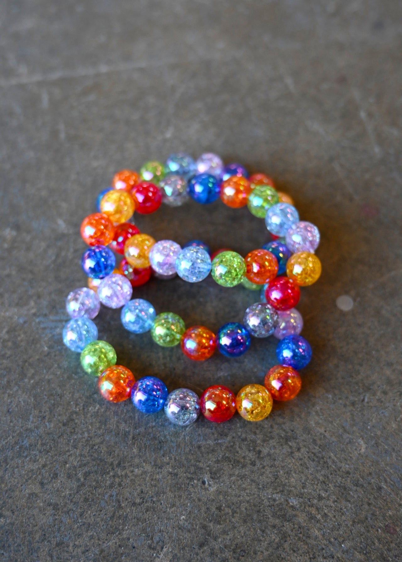 A bundle of 3 bracelets with multi-color beads on a dark background