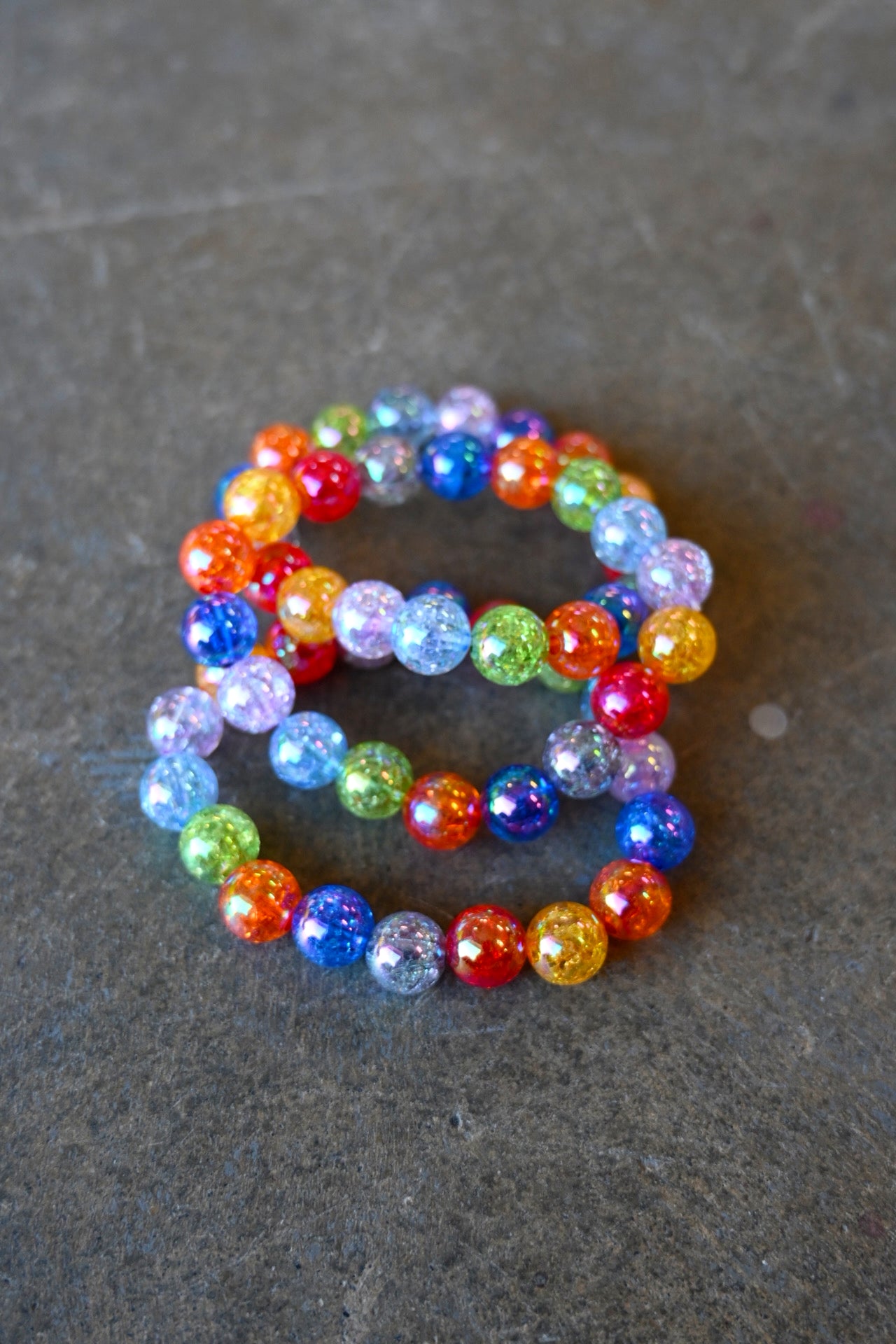 A bundle of 3 bracelets with multi-color beads on a dark background