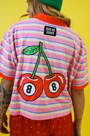 A person shown from the back wearing a pink striped short-sleeve shirt with a large cherry graphic on the back, featuring two red cherries with number 8s inside them. The shirt has a black 'burn toast' brand label near the collar