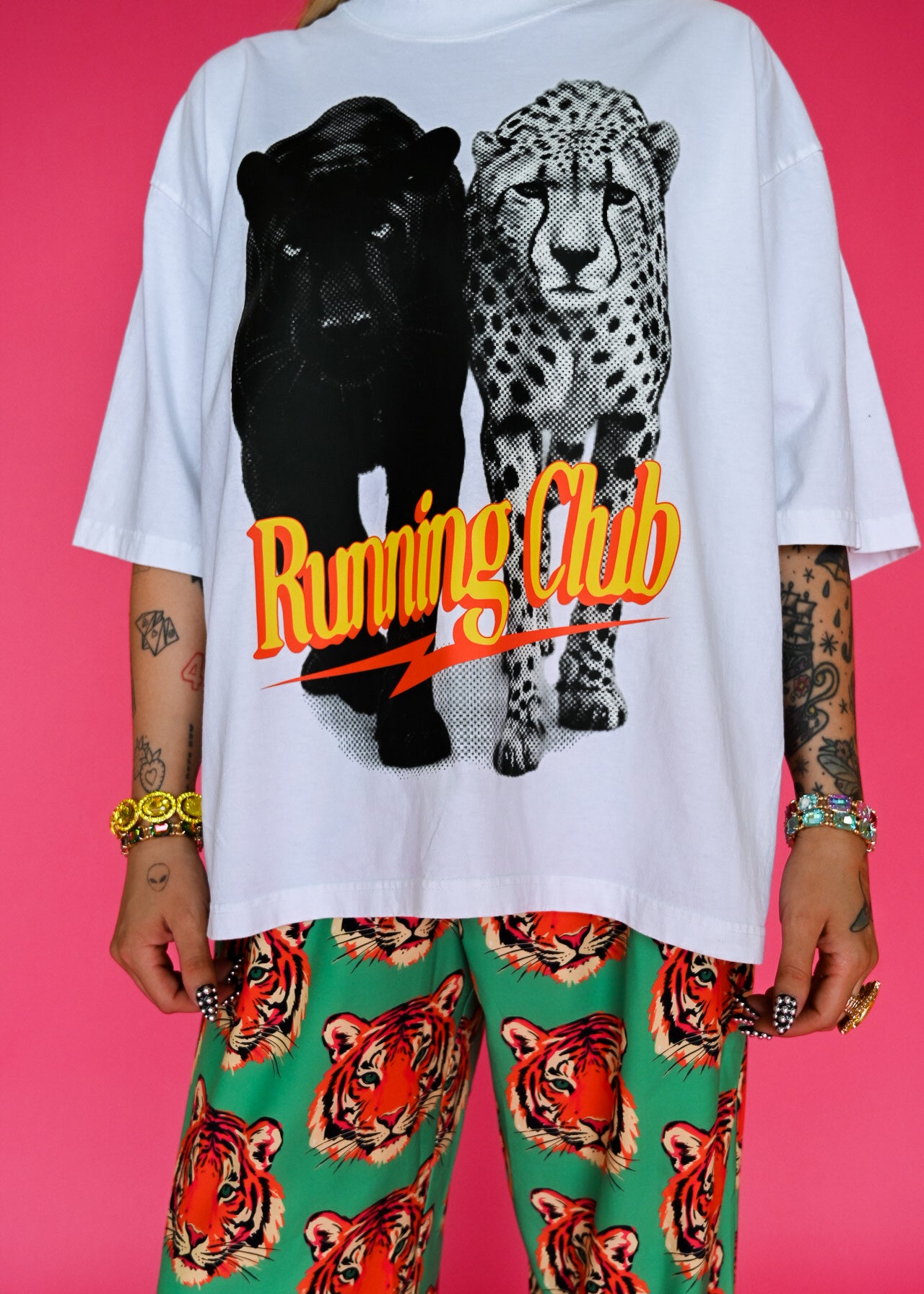 yellow, paired with green pants featuring a tiger face pattern, against a solid pink background