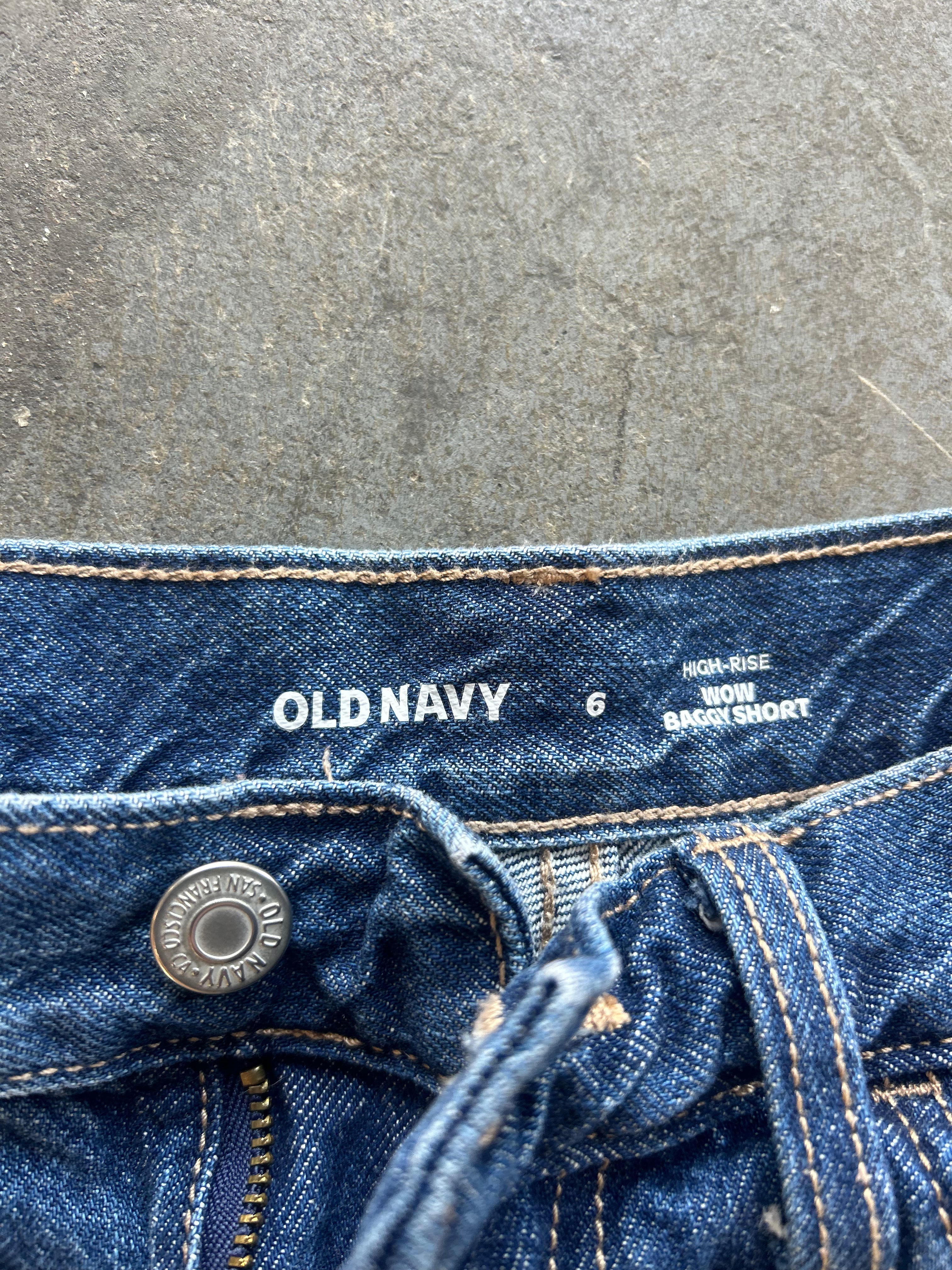 Close-up of the waistband of a pair of Old Navy high-rise blue denim jeans, showing the brand name, size 6, and white contrast stitching against a gray textured background