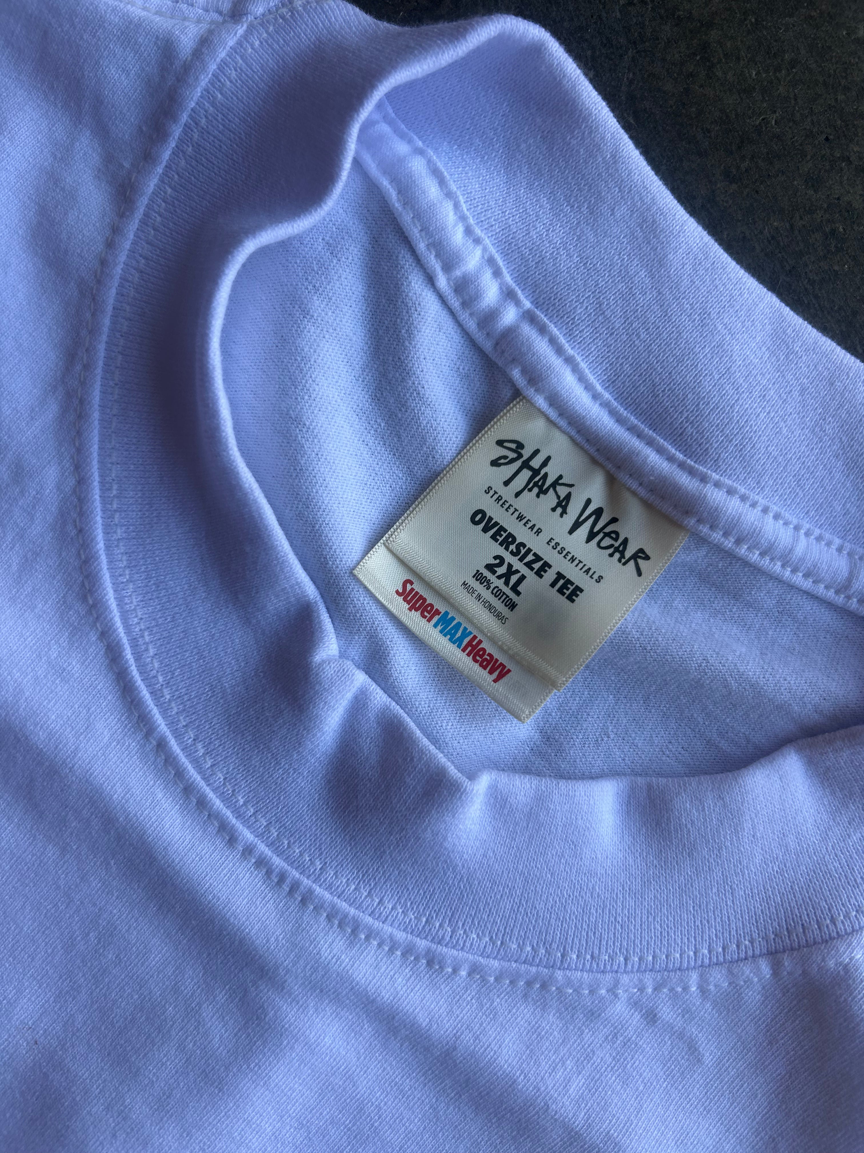 Close-up of a light lavender crewneck t-shirt showing the inner neck label which reads 'SHAKA WEAR' and 'OVERSIZE TEE 2XL'.