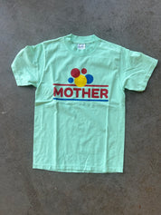 Seafoam green graphic tee with MOTHER logo on a concrete floor