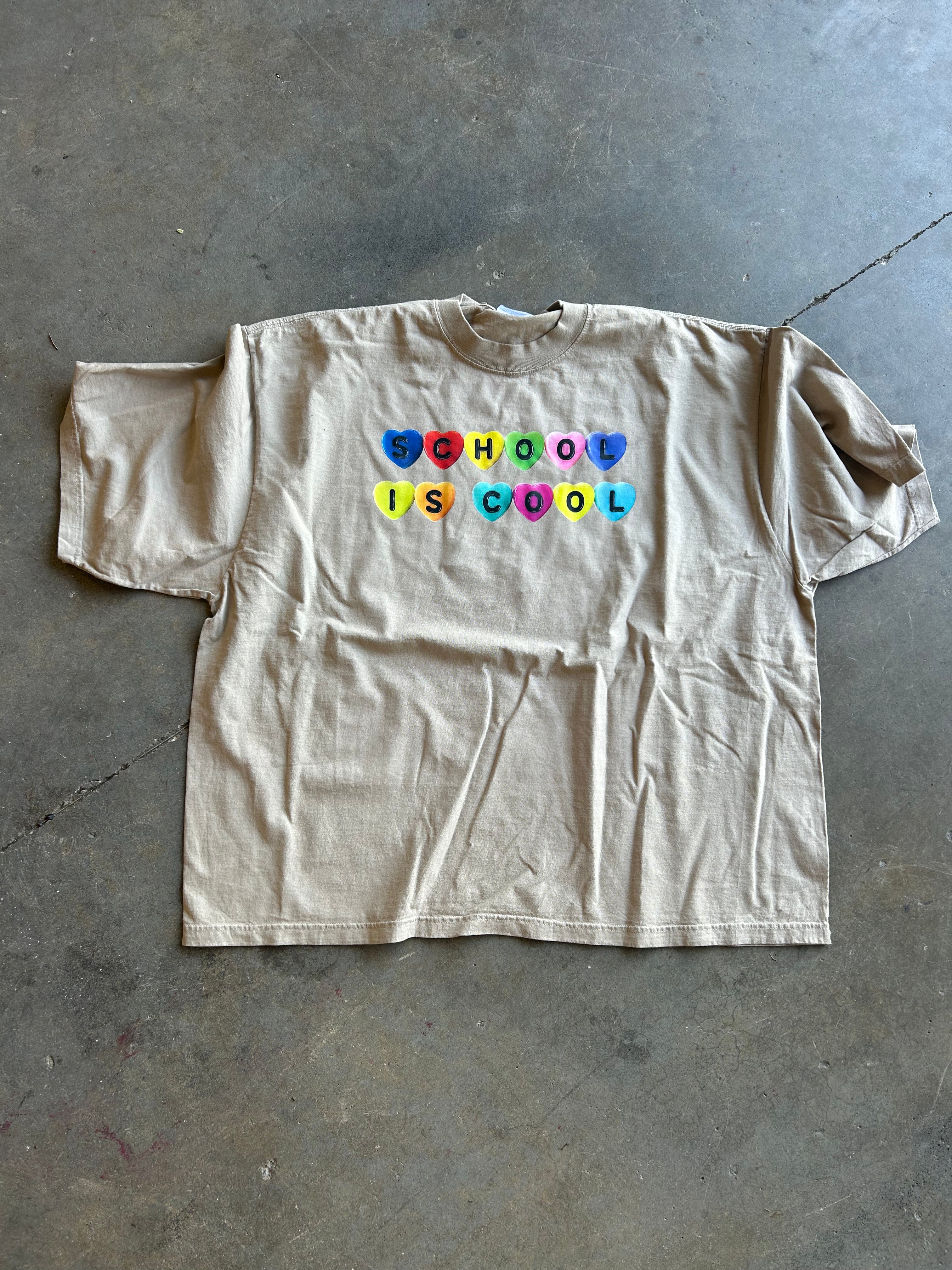 Oatmeal colored graphic that says School is Cool In candy hearts on a concrete Surface