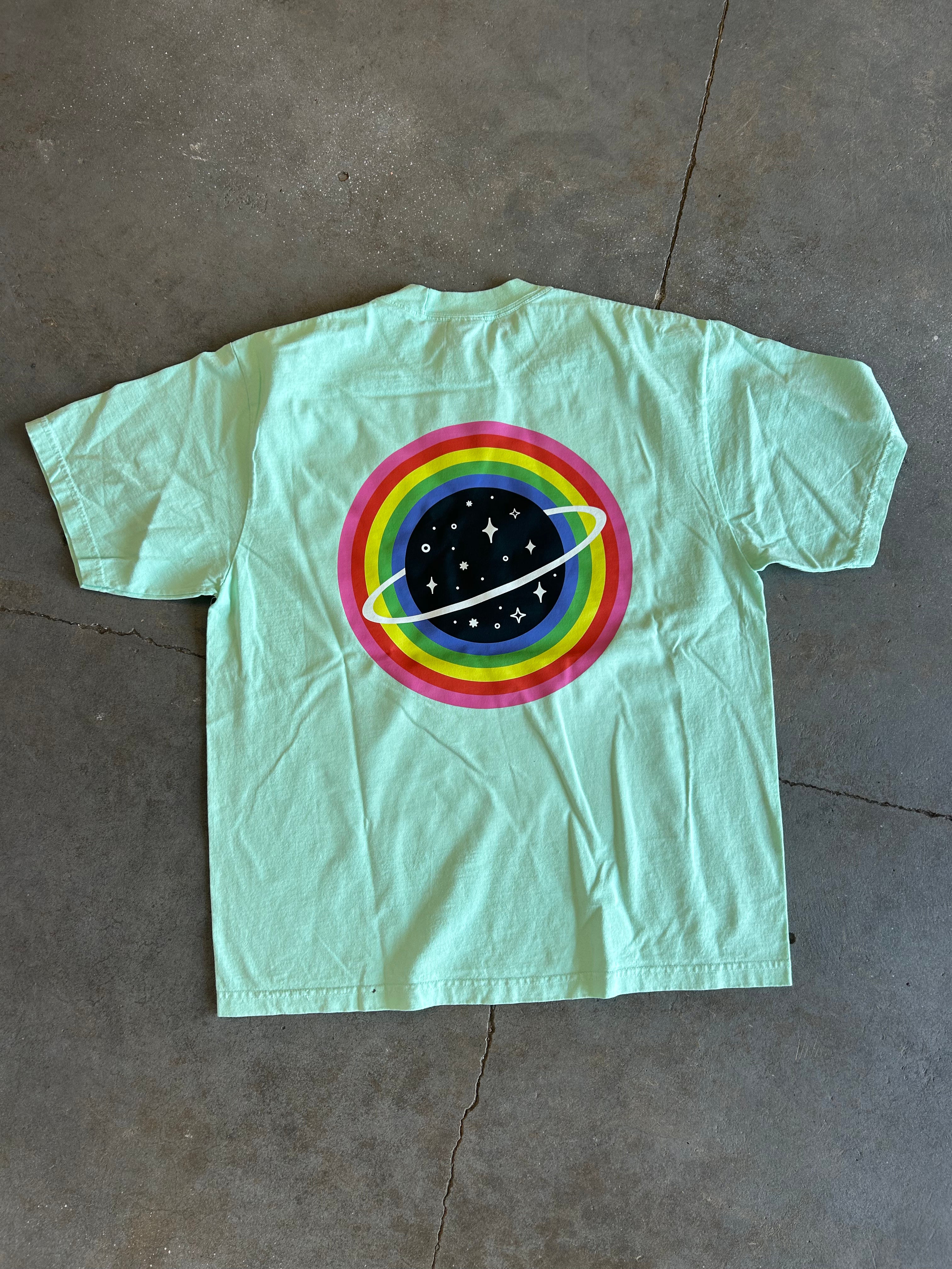 Planet graphic on the back of a seafoam green shirt on a concrete surface