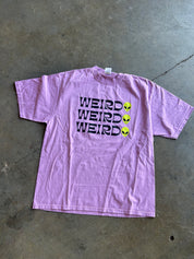 Weirdo x3 graphic on a purple shirt on a concrete floor