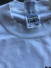Close-up of the inside collar of a white heavyweight T-shirt showing the inner neck labels. One label reads 'FAMOUS HEAVYWEIGHT T-SHIRTS' and the other mentions 'Shaka Wear'.