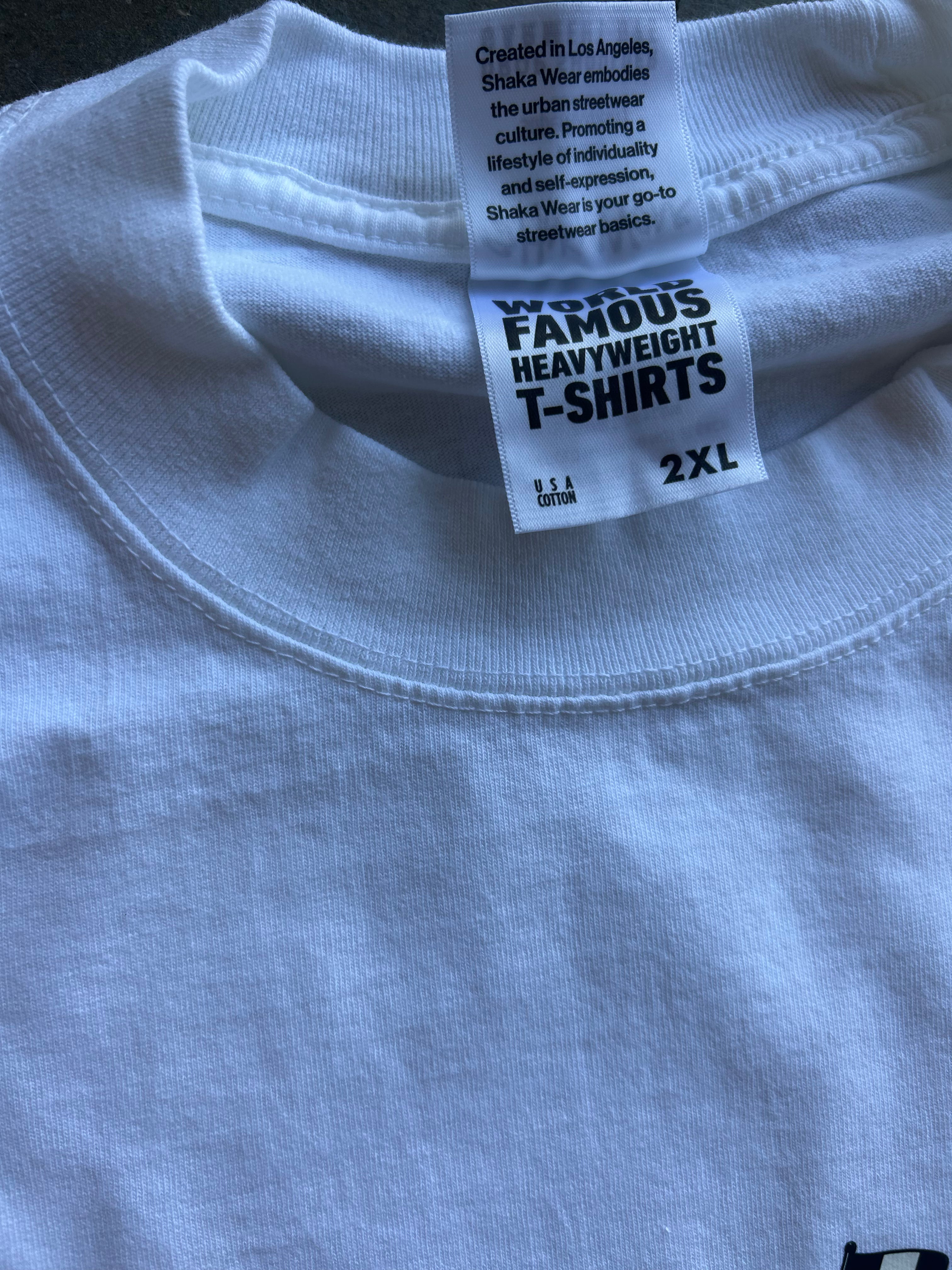 Close-up of the inside collar of a white heavyweight T-shirt showing the inner neck labels. One label reads 'FAMOUS HEAVYWEIGHT T-SHIRTS' and the other mentions 'Shaka Wear'.