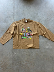 Long sleeve brown tee with Get Lost graphic on a concrete surface