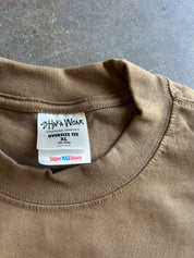Close-up of a brown crewneck t-shirt showing the inner neck label which reads 'shaka Wear' and 'SuperMAX Heavy'.