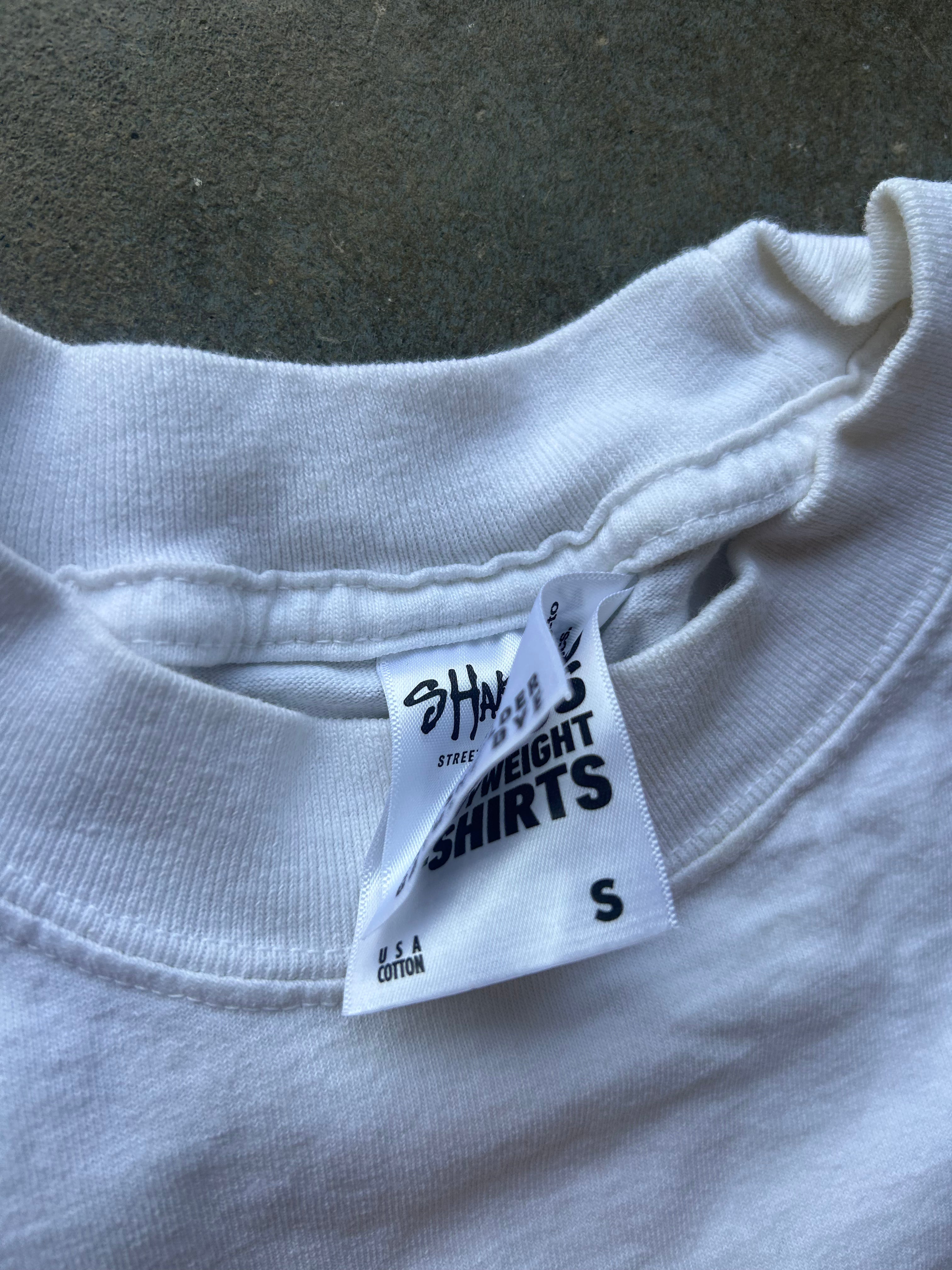 Close-up of a white crewneck t-shirt showing the inner neck label which reads 'SHADYSUNWEIGHT SHIRTS' and 'S'.