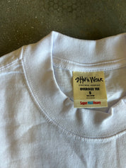 Close-up of a white oversized crewneck t-shirt collar showing the inner neck label which reads 'SHAKA WEAR' and 'OVERSIZE TEE S'.