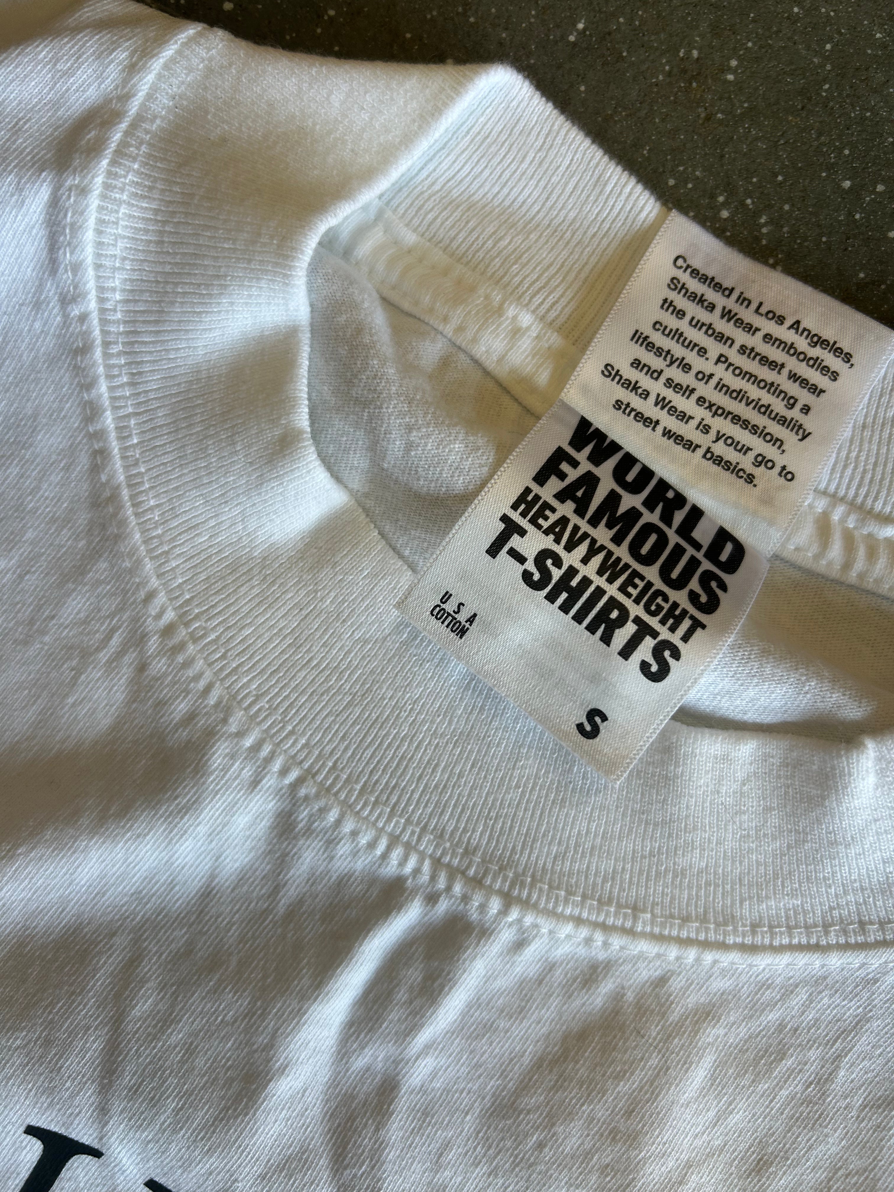 Close-up of a white t-shirt collar showing the inner neck label which reads 'WORLD FAMOUS HEAVYWEIGHT T-SHIRTS' and 'S'.