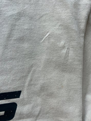 Close-up of a light gray heather fabric surface with a small black graphic fragment visible at the bottom left and a few minor scuffs or marks on the material.