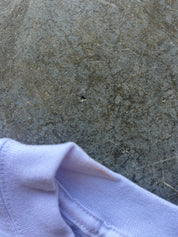 A close-up of a white shirt, shown against a textured gray concrete or stone surface.