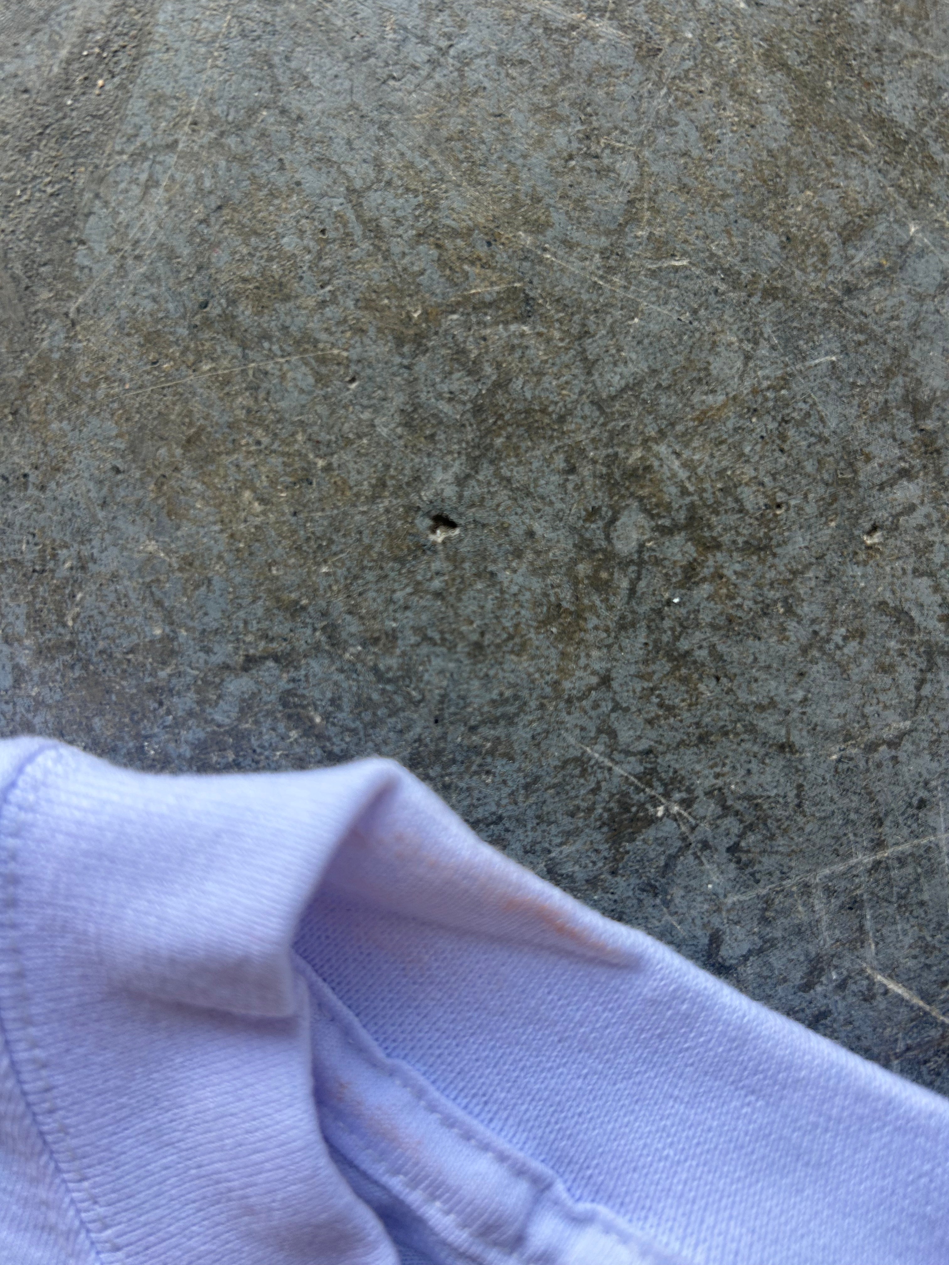 A close-up of a white shirt, shown against a textured gray concrete or stone surface.