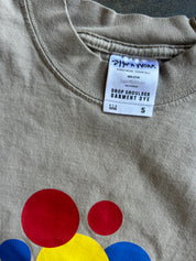 Close-up of a beige crewneck sweatshirt with a colorful graphic of red, yellow, and blue circles at the bottom, showing the brand tag 'DHW Work'.