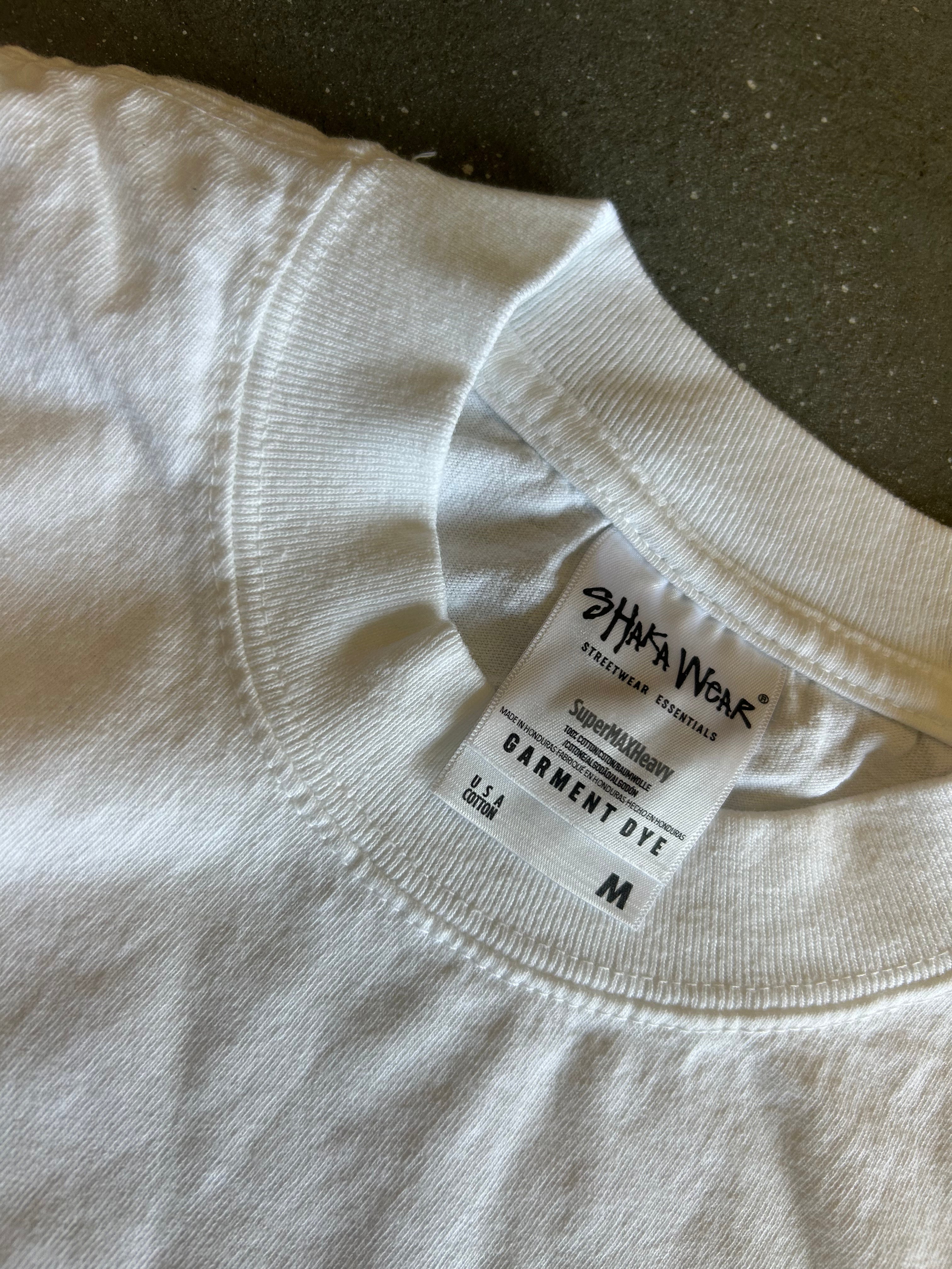 Close-up of a white crewneck t-shirt showing the inner neck label which reads 'SHAKA WEAR' and 'GARMENT DYE'.