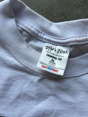 Close-up of a light gray cropped t-shirt showing the inner neck label which reads 'SHAKA WEAR' and 'SuperMAX Heavy'.
