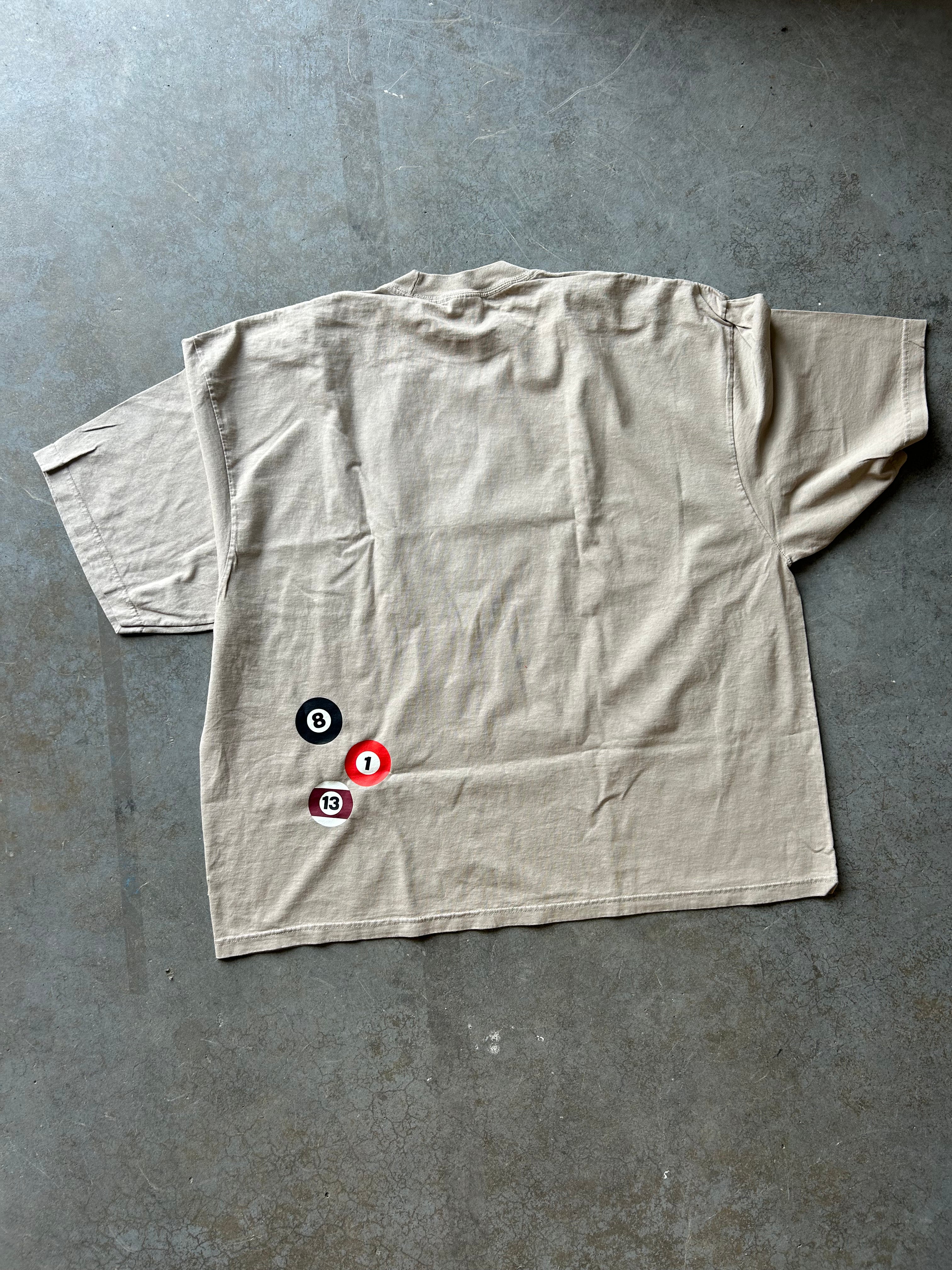 Back of a tshirt that has 8 ball design, flat lay view on a concrete