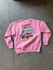 A pink crewneck sweatshirt with a colorful graphic print of a muscle car and the text 'Engine of the Hot Wheels' and 'Fast Lane 95', laid flat on a gray concrete floor.