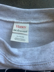 Close-up of the inside collar of a light gray ribbed t-shirt, showing the white Hanes eco-smart brand tag and size information (XL/TG/XG).