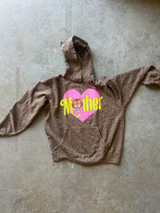 A brown leopard-print hoodie laid flat on a textured gray concrete floor, featuring a pink heart graphic on the chest with the word 'Nether' in yellow and a tiger face illustration.