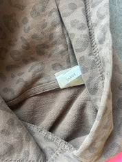 Close-up of a leopard print fabric garment in taupe and brown, showing the interior neckline with a small size tag reading LARGE.