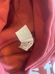Close-up of a folded sweatshirt showing the interior collar and a white care label sewn inside. The fabric is a muted dusty rose or mauve pink color.