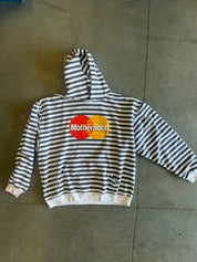 A black and white horizontally striped hoodie with a 'MotherHood' graphic printed on the chest, laid flat on a gray concrete floor.