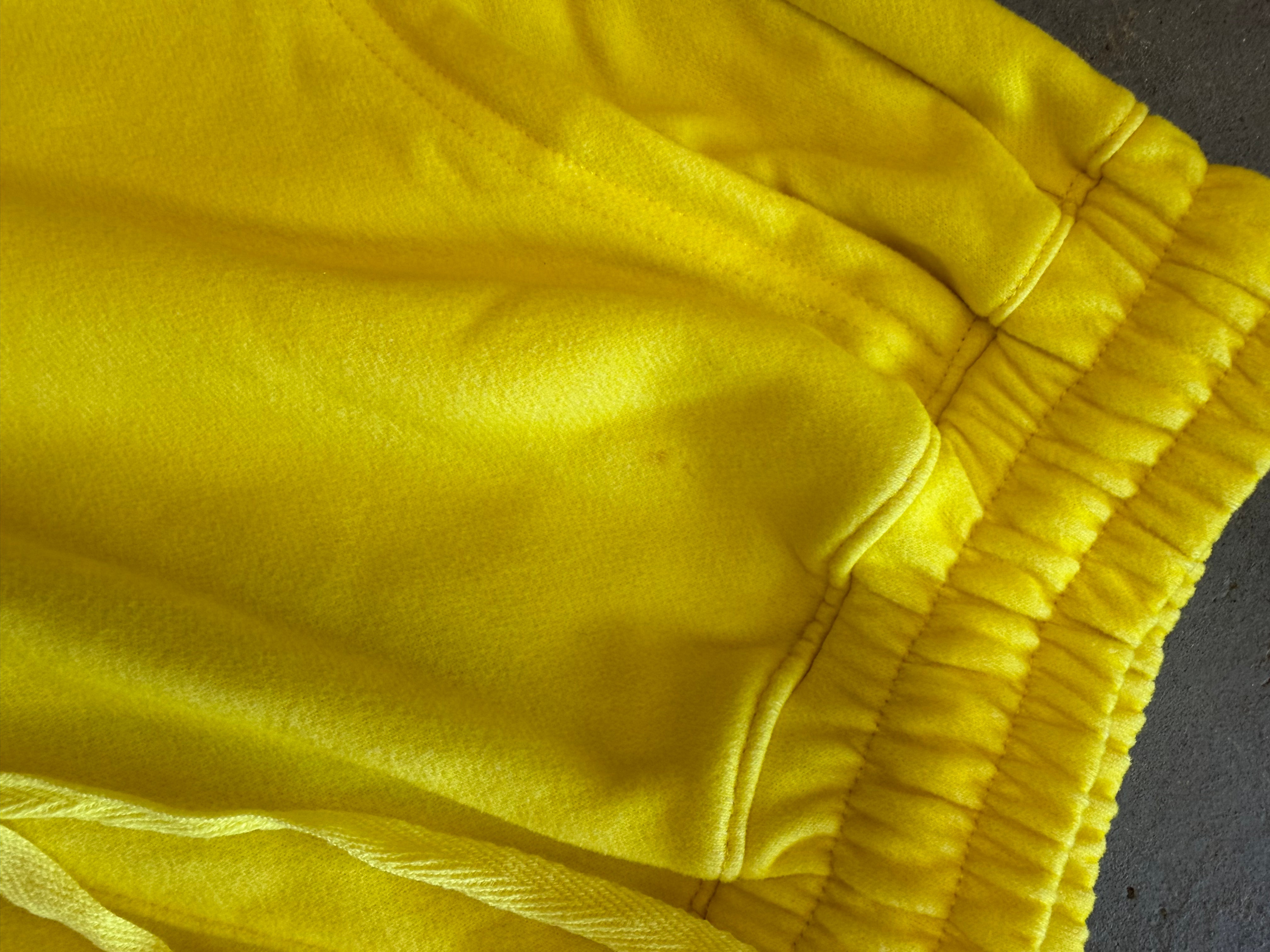 Close-up of bright yellow fabric with an elasticized waistband and drawstring detail