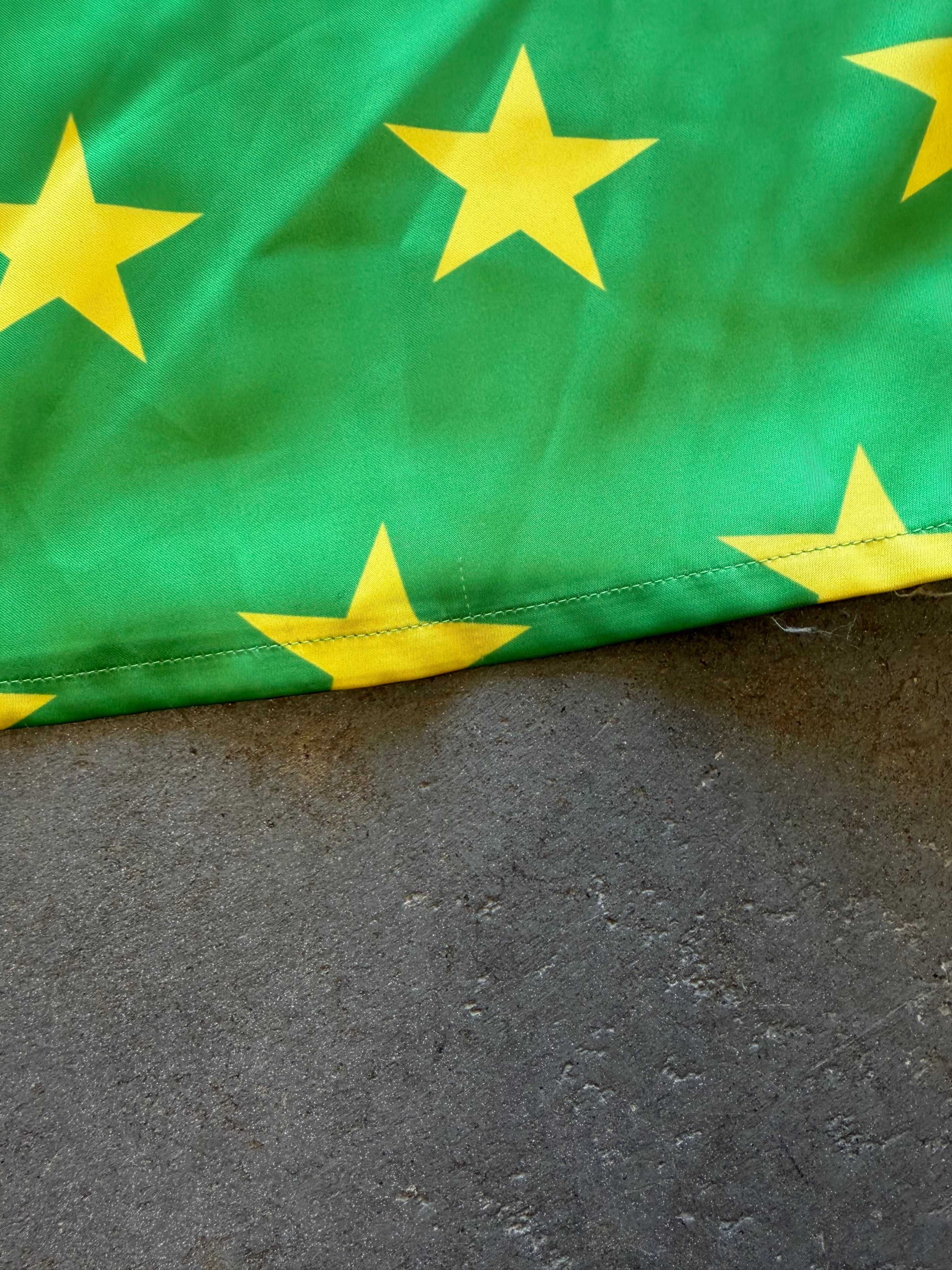 A close-up of a green fabric item printed with large yellow stars, laid over a dark gray textured surface