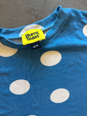 Close-up of a blue ribbed knit top with large white polka dots and a visible Burnt Toast neck label