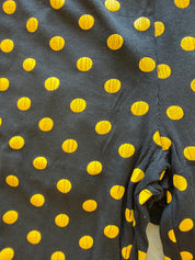 Close-up of a dark charcoal gray ribbed fabric with a repeating pattern of bright yellow polka dots