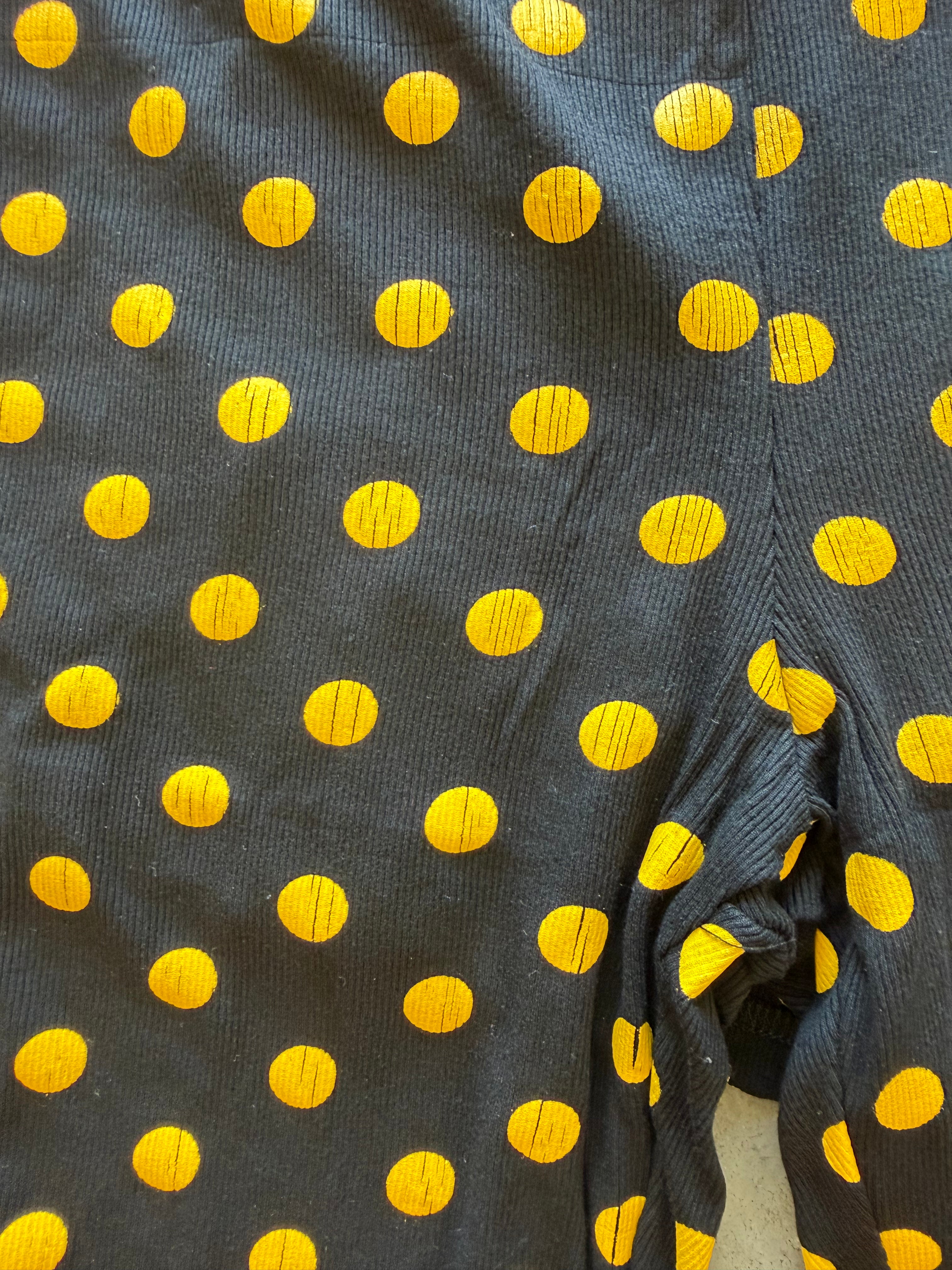 Close-up of a dark charcoal gray ribbed fabric with a repeating pattern of bright yellow polka dots