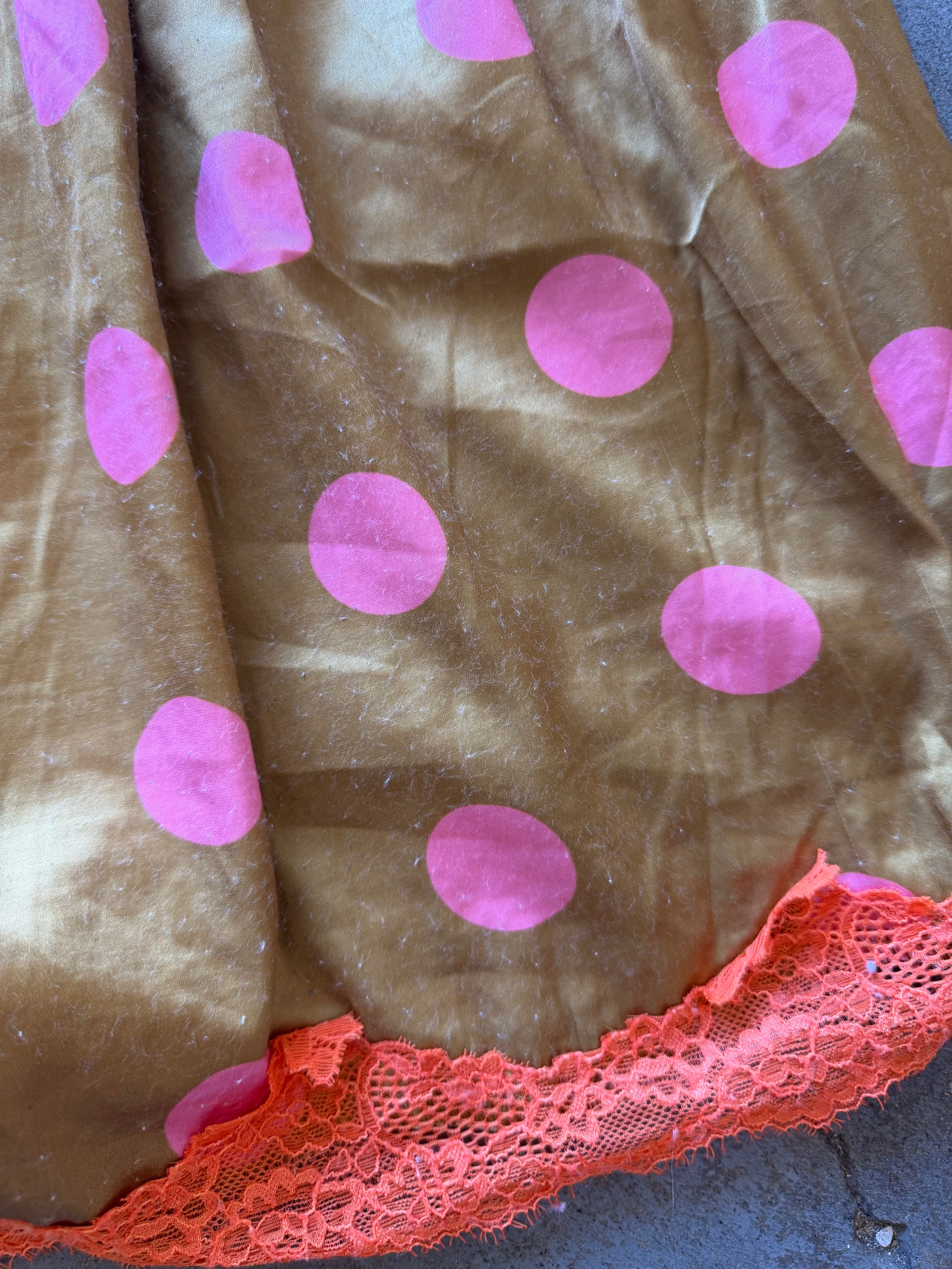 Brown velvet fabric with large pink polka dots and a bright coral lace trim along the edge