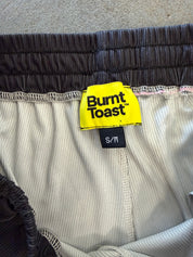 Close-up of a pair of Burnt Toast shorts showing the waistband, interior lining, and a bright yellow brand label.
